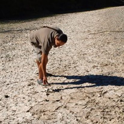 Cowichan community member Tim Kulchyski inspects dry Cowichan Riverbed.